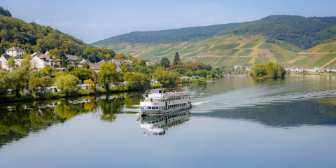 Blick von der Fußgängerbrücke auf ein Schiff mit der Moselinsel im Hintergrund